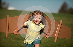 Child boy playing with plane wings outdoors. Cute boy playing pilot and dreaming of becoming a spaceman aviator pilot