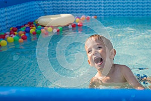 Child boy playing in small baby pool.baby swim and splash. Happy little boy playing with water toys on hot summer day. Family