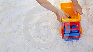 Child boy playing with a toy truck close-up, in slow motion, on a white background