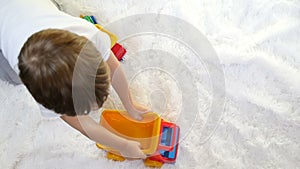 Child boy playing with a toy truck, in slow motion, on a white background