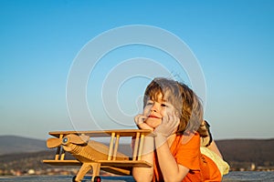Child boy playing with wooden toy airplane, dream of becoming a pilot. Childrens dreams. Child pilot aviator with wooden
