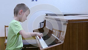 Child boy practicing playing piano in music lesson at musical class at school.