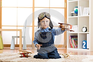 Child boy pretending to be pilot. Kid playing with toy airplanes at home. Travel and dream concept