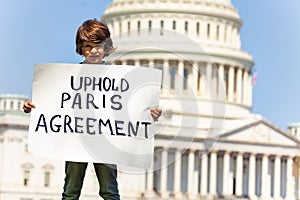 Protester holding sign uphold Paris agreement in hands photo