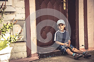 Child boy punished sad boring sitting lonely on door steps