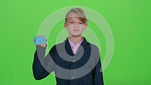 Child boy raises his hand and shows the card on a green screen