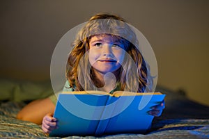 Child boy reading book. Child reading a book in bed before going to sleep. Child reading a book on bedtime night. Boy