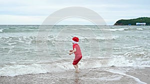 Child boy in red cloth and Santa Claus hat enjoying Christmas on the beach on Xmas travel vacation. Christmas or New