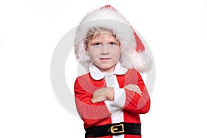 A child boy in a red suit and a santa claus hat stands with his hands on his chest. Positive story about Christmas and New Year