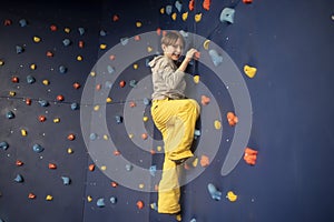 child, boy rises, climbs on a blue climbing wall