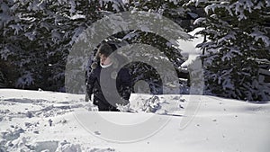 Child boy rolls and tumbles in the snow in the forest. Boy playing in the snow. Slow motion