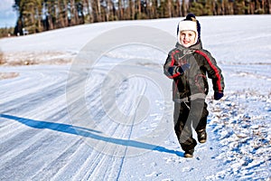 Child boy running along the road in winter