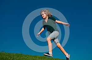 Child boy running on grass field and dreaming. Kids play on summer field. Active kids healthy outdoor. Fun activity.