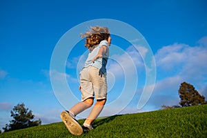 Child boy running on meadow. Happy kid run on beautiful summer field. Back view.