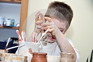 Child boy shaping clay in pottery studio