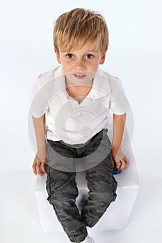 A child boy sitting a block with an innocent cute attitude.