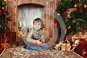 Child boy sitting under the Christmas tree with gift box