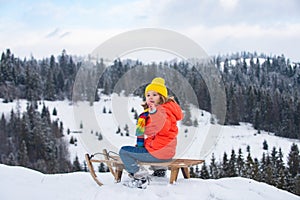 Child boy sledding in winter. Kid riding on snow slides in winter.