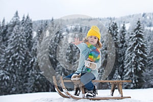 Child boy sledding in winter, playing with snowball. Kid riding on snow slides in winter. Winter christmas forest with