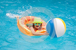 Child boy splashing in swimming pool. Swim water sport activity on summer vacation with children.