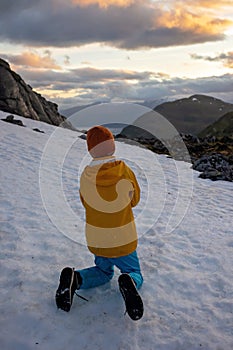 Child, boy, standing backwards, enjoying snow on mount Hoven, splendid view over Nordfjord from Loen skylift