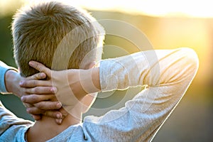 Child boy standing outdoors on summer sunny day enjoying warm weather outside. Rest and wellness concept