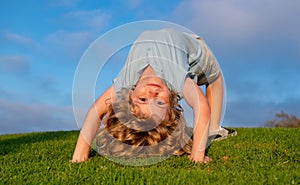 Child boy standing upside down on green grass in summer Park. The concept of a healthy family lifestyle. The fun and