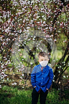 Child boy stands with a medical protective respirator on his fac