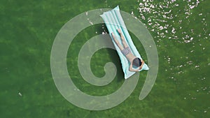 child boy in striped swimming trunks floats on a blue air mattress