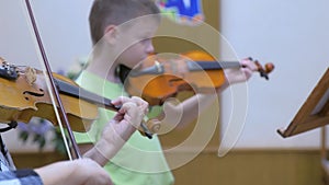 Child boy student playing violin with teacher in music lesson at musical school.