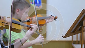 Child boy student playing violin with teacher in music lesson at musical school.