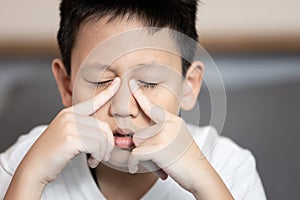 Child boy suffering chronic Rhinosinusitis,Rhinitis or acute Sinusitis,pain in nasal cavity,nose bridge sore,aching eye socket, photo