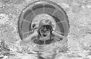 Child boy swim with float ring in swimming pool. Kids summer holidays and vacation concept. Happy little boy with