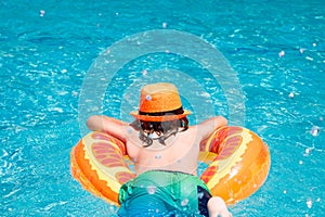 Child boy swim with floating ring in swimming pool. Kids summer vacation. Happy little boy with inflatable ring in