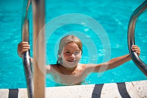 Child boy swim in swimming pool. Activities for happy children on the pool.