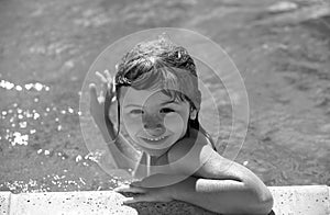 Child boy swim in swimming pool. Happy little kid boy playing with in outdoor swimming pool on hot summer day. Kids