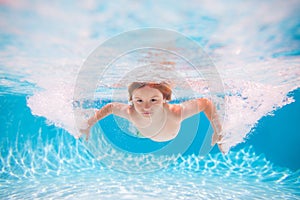 Child boy swim under water in sea. Kid swimming in pool underwater. Happy boy swims in sea underwater, active kid