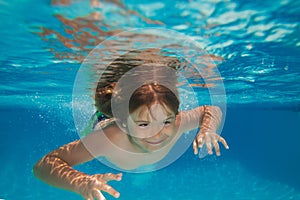 Child boy swim under water in sea. Kid swimming in pool underwater. Happy boy swims in sea underwater, active kid