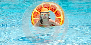 Child boy in swimming pool with inflatable toy ring. Kids swim on summer pool. Beach sea and water waves background.