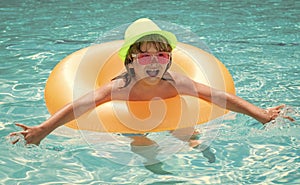 Child boy in swimming pool with inflatable toy ring. Kids swim on summer vacation. Swim for child on float. Beach sea
