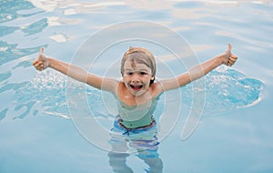 Child boy in swimming pool playing in water. Vacation and traveling with kids. Children play outdoors in summer.