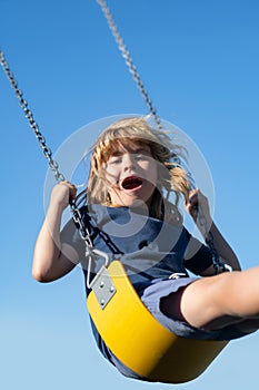 Child boy on swing. Little kid swinging on playground. Happy cute excited child on swing. Cute child swinging on a swing