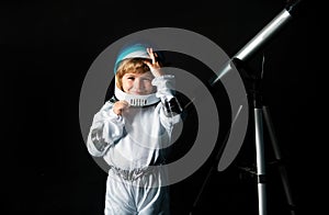 Child boy with a telescope imagines himself to be an astronaut in an space helmet. Astronomy and astrology concept.
