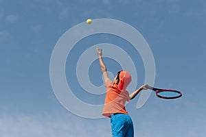 Child boy tennis player with racket serve ball. Kids sport tennis game. Child athlete in action. Background copy space