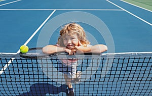 Child boy with tennis racket and ball on tennis court outdoor. Sport exercise for kids. Summer activities for children.
