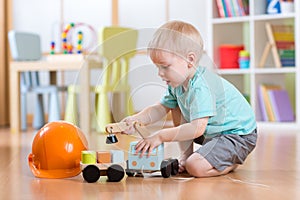 Child boy toddler playing with toy car indoors