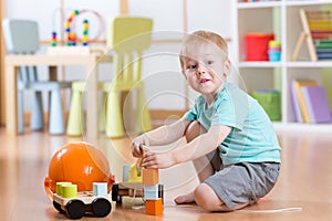 Child boy toddler playing with toy car indoors