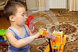 Child boy toddler playing with toy car indoors