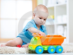 Child boy toddler playing with toy car in nursery