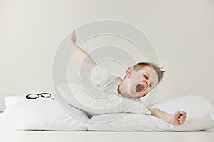 child boy wakes up and stretching on his comfortable bed in morning, Health care and good morning world concept